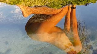 Güneş batarken okyanus kıyısındaki yansımada esneyen çıplak Yoga